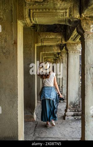 Un turista cattura la bellezza dei corridoi di Angkor Wat, rivelando l'intricata architettura dell'antico tempio. Foto Stock