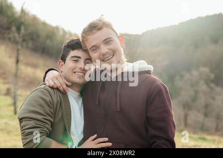 Una coppia felice gode di una giornata di sole all'aperto, condividendo un sorriso e un caldo abbraccio in uno splendido ambiente naturale Foto Stock