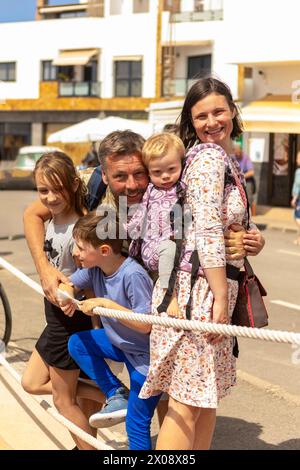 Una famiglia sorridente si lega con il suo bambino con la sindrome di Down, circondato da amore e sostegno durante un'attività all'aperto. Foto Stock