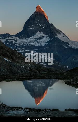 Sereno crepuscolo sul lago Riffelsee con l'iconico Cervino riflesso sulla superficie calmo dell'acqua di Zermatt, Svizzera Foto Stock