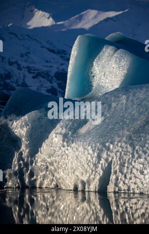 Un'immagine impressionante che cattura la bellezza serena di un ghiacciaio che si riflette sulle acque tranquille sotto il soffice bagliore della luce solare in Islanda Foto Stock