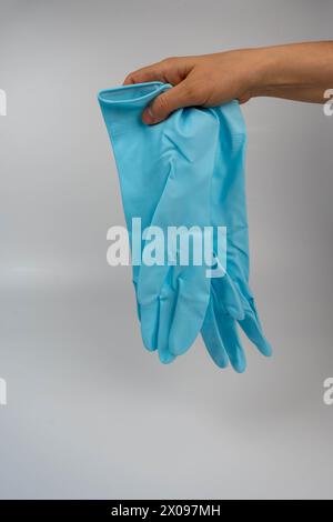 mani di donna che indossano guanti in gomma dai colori turchesi durante i lavori domestici o le pulizie, con particolare attenzione alla superficie ruvida della g Foto Stock