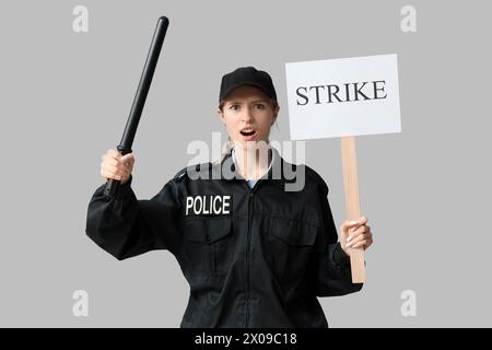 Protesta contro un agente di polizia che tiene in mano il bastone e il cartello con il testo su sfondo grigio Foto Stock