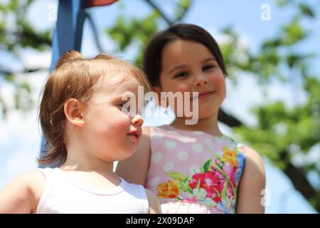 Lo spirito gioioso e spensierato di due bambine che si divertono insieme nel parco giochi durante una giornata estiva di sole. Foto Stock