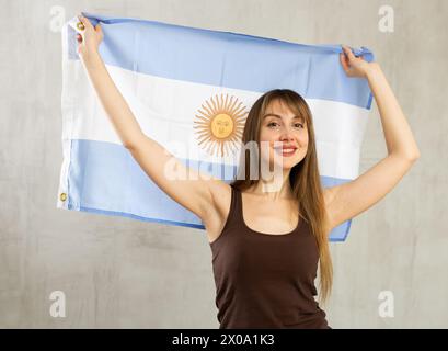 Ritratto di felice donna di Argentina partita sventolando bandiera nazionale Foto Stock