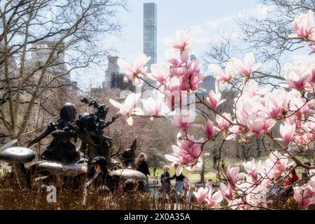 La scultura Alice nel Paese delle meraviglie del Tea Party è circondata da alberi in fiore all'inizio della primavera, Central Park, 2024, New York City, USA Foto Stock