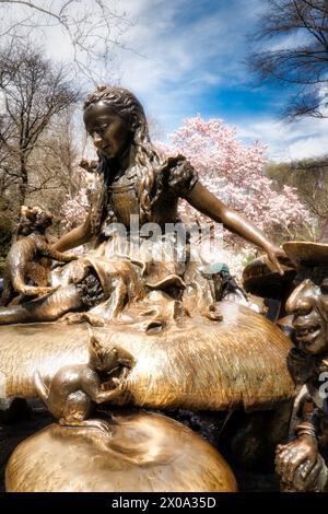 La scultura Alice nel Paese delle meraviglie del Tea Party è circondata da alberi in fiore all'inizio della primavera, Central Park, 2024, New York City, USA Foto Stock