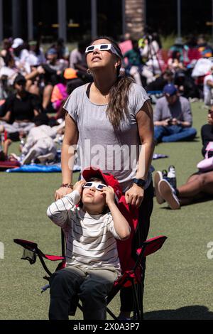 Atlanta, GA / USA - 8 aprile 2024: Madre e figlio guardano attraverso occhiali speciali per vedere l'eclissi solare totale ad una festa di orologi l'8 aprile 2024. Foto Stock