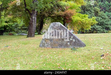 Queenstown, nuova Zelanda- 3 aprile 2024: Monumento in pietra con una targa, significa una capsula del tempo del 1990, annidata tra gli alberi autunnali di Queenstow Foto Stock