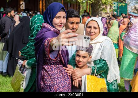 Srinagar, India. 10 aprile 2024. I musulmani kashmiri hanno visto fare selfie dopo le preghiere di Eid-al-Fitr fuori da una moschea a Srinagar. Il festival EID-al-Fitr segna la fine del santo mese di digiuno del Ramadan. Nel frattempo, le autorità indiane hanno impedito alle persone di offrire preghiere Eid-al-Fitr nella storica grande Moschea del Kashmir, o Jamia Masjid, per il quinto anno consecutivo nel centro di Srinagar. Credito: SOPA Images Limited/Alamy Live News Foto Stock