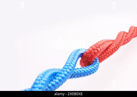 Corda, legature e connessione con il colore in nodo, collegamento o loop insieme su sfondo bianco in collaborazione. Blu, rosso e unisci la stringa in un'unità astratta Foto Stock