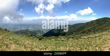 Una splendida vista sulle montagne in una giornata di sole e montagne verdeggianti con splendide nuvole. Foto Stock