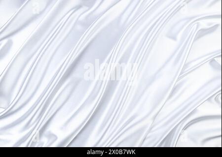 Lussuoso sfondo bianco satinato. Tessuto di seta morbido ed elegante. Tessuto ondulato. Vista dall'alto. Foto Stock