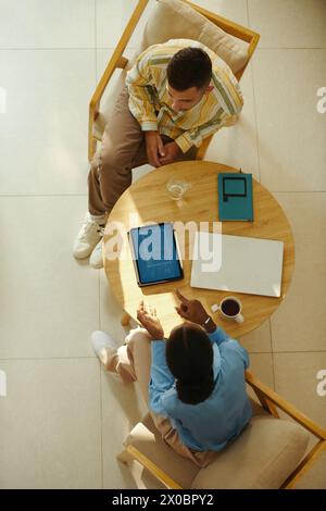 Colleghi d'affari seduti a un tavolino e discutono idee per lo sviluppo delle startup Foto Stock