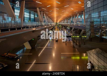 Terminal dell'aeroporto internazionale di Hamad con tutti i cancelli e i viaggiatori che passano. Foto Stock