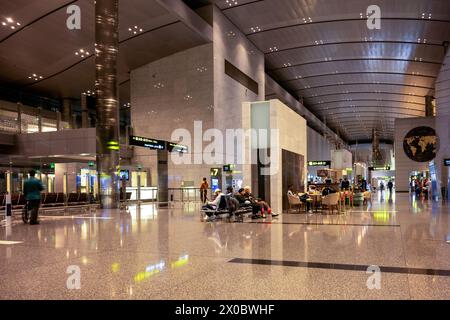 Terminal dell'aeroporto internazionale di Hamad con tutti i cancelli e i viaggiatori che passano. Foto Stock