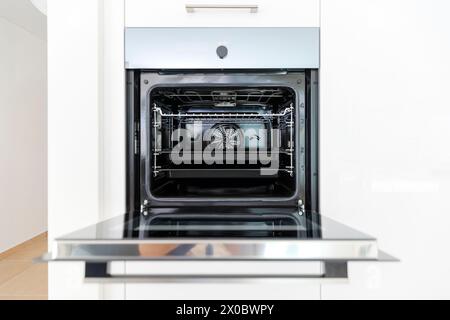 Dettaglio di un nuovo forno aperto con due vassoi da forno all'interno. Interno di una moderna cucina bianca. Nessuno dentro Foto Stock