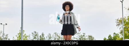 Giovane donna afroamericana con capelli ricci afro che cavalca uno skateboard in uno skate Park. Foto Stock