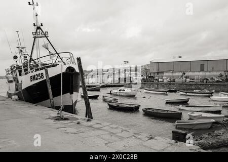 Immagine in bianco e nero di un peschereccio attraccato su una banchina di pesci per riparazioni a Teignmouth, Devon, sul fiume Teign. Foto Stock