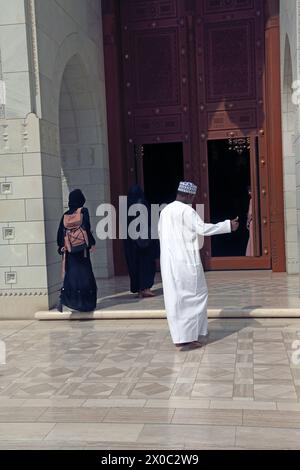 La grande Moschea del Sultano Qaboos Oman indossa un Dishdasha e un Kummah che entrano attraverso la porta di legno Muscat Oman Foto Stock