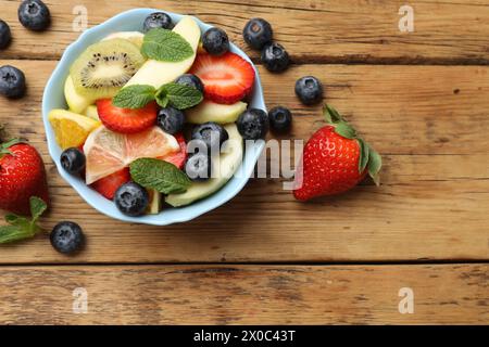 Gustosa Macedonia di frutta nel recipiente e ingredienti su un tavolo di legno, in piano Foto Stock