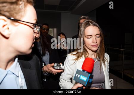 Una donna politica statunitense sicura di sé risponde alle domande della stampa e rilascia un'intervista per i media che camminano nel corridoio dell'edificio governativo. Delegazione americana circondata da una folla di giornalisti. Campagna stampa. Foto Stock