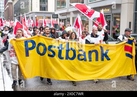 Amburgo, Germania. 11 aprile 2024. I partecipanti a una marcia dimostrativa attraverso il centro di Amburgo durante uno sciopero di avvertimento a Postbank. Lo sciopero fa parte di un'ondata nazionale di scioperi da parte del sindacato Verdi per aumentare la pressione sul datore di lavoro nei negoziati salariali in corso dopo che il terzo ciclo di negoziati si è concluso senza un accordo. Credito: Bodo Marks/dpa/Alamy Live News Foto Stock