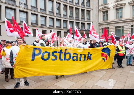 Amburgo, Germania. 11 aprile 2024. Durante uno sciopero di allerta a Postbank, i partecipanti a una dimostrazione si trovano di fronte a un edificio della Deutsche Bank durante un raduno provvisorio. Lo sciopero fa parte di un'ondata nazionale di scioperi da parte del sindacato Verdi per aumentare la pressione sul datore di lavoro nei negoziati salariali in corso dopo che il terzo ciclo di negoziati si è concluso senza un accordo. Credito: Bodo Marks/dpa/Alamy Live News Foto Stock