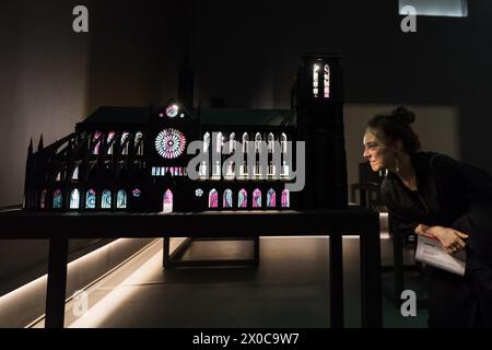 LONDRA, REGNO UNITO - 11 APRILE 2024: un viisitore guarda "Notre-Dame", un passato di una nuova installazione su larga scala intitolata "Sanctuary City" (2024) composta da edifici in miniatura che rappresentano luoghi di rifugio per gruppi perseguitati e vulnerabili durante un photocall per la mostra "Stati sospesi" di Yinka Shonibare a Serpentine South a Londra, Regno Unito, l'11 aprile 2024. La prima mostra personale del lavoro di Shonibare in un'istituzione pubblica di Londra da oltre 20 anni esplora temi centrali dei lasciti del potere coloniale, dei siti di rifugio e rifugio, nonché l'impatto ecologico del colo Foto Stock