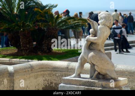 Tarragona, Spagna - 11 aprile 2024: Un'elegante scultura che ritrae un legame senza tempo si erge in primo piano davanti a un vibrante ambiente costiero, offrendo una vista Foto Stock