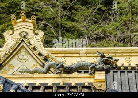 Un drago d'oro è arroccato sul tetto di un edificio. Il drago è circondato da intricati disegni e accenti dorati, dando all'edificio un senso di gra Foto Stock