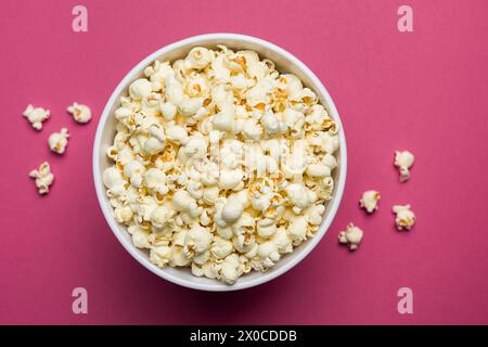 Popcorn salato in secchio classico su sfondo magenta. Foto Stock