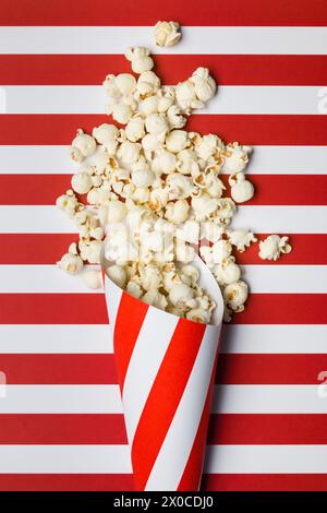 Composizione piatta con popcorn su sfondo a strisce rosse e bianche. Foto Stock