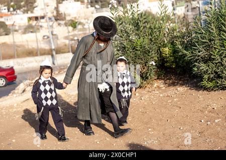 Gerusalemme Est, Gerusalemme, Israele. 5 novembre 2010. Un colono ebreo ortodosso cammina con i bambini nello sceicco Jarrah. Lo sceicco Jarrah, un piccolo quartiere palestinese adiacente alla città vecchia di Gerusalemme, a Gerusalemme Est, tiene frequenti proteste in quanto i cittadini musulmani lamentano che le norme amministrative israeliane discriminano i musulmani, che hanno popolato l'area per secoli e favoriscono i nuovi coloni ebrei. (Credit Image: © Dominika Zarzycka/SOPA Images via ZUMA Press Wire) SOLO PER USO EDITORIALE! Non per USO commerciale! Foto Stock