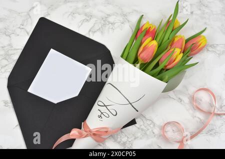 Foglio di carta da riempire con il contenuto. Bouquet di tulipani avvolti in carta con nastro e busta. Foto Stock