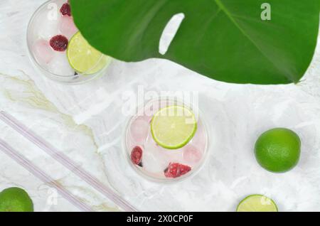 Drink con vista dall'alto decorati con fette di lime e lamponi. Foglia di Monstera. Foto Stock