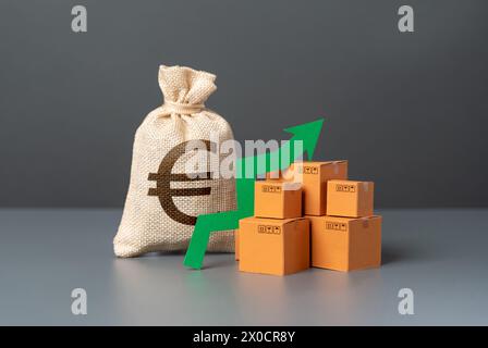 Scatole con una freccia verde verso l'alto vicino a un sacchetto di denaro in euro. Elevata domanda di beni. Importazione ed esportazione. Crescita economica e aumento delle vendite. Buone vendite, grande inco Foto Stock