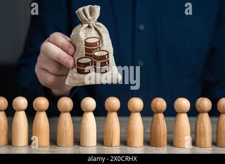 Un uomo tiene un sacco di monete al di sopra della folla. Depositi e prestiti. Fondi di bilancio per la politica sociale. Crowdfunding e raccolta fondi. Politica sociale. Foto Stock