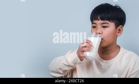 Concetto di buona nutrizione felice, Ritratto di un bambino piccolo e bello in camicia color crema, tenere bere il mockup scatola del latte, isolato su ba bianca Foto Stock