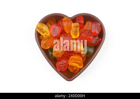 caramelle dolci multicolore in ciotola a forma di cuore su sfondo bianco, vista dall'alto. Spazio per il testo Foto Stock