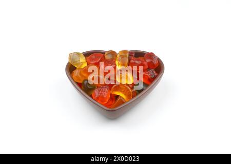 caramelle dolci multicolore in ciotola a forma di cuore su sfondo bianco, vista dall'alto. Spazio per il testo Foto Stock