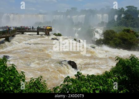 I visitatori si affacciano sulle potenti cascate di Iguazu al loro apice di potenza. Foto Stock