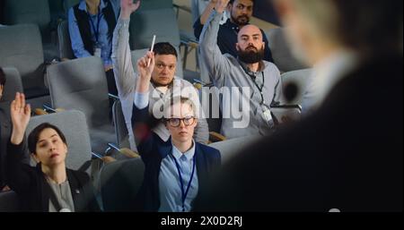 Primo piano del presidente, politico o attivista che rilascia un colloquio per la televisione o i media dal palco nella sala conferenze. Diversi giornalisti alzano la mano e fanno domande durante la campagna stampa. Foto Stock