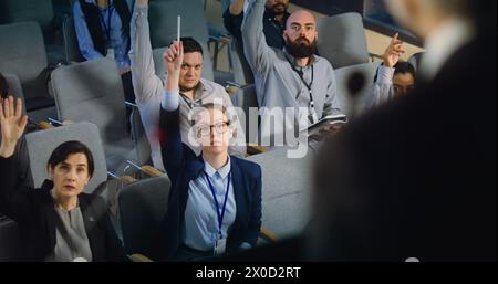 Diversi giornalisti, operatori dei media alzano la mano e fanno domande durante la conferenza stampa con un politico. L'addetto stampa o attivista rilascia un colloquio per la televisione nella sala dell'edificio governativo. Primo piano Foto Stock