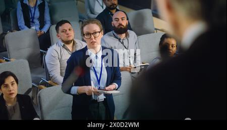 Primo piano del presidente, politico o attivista che rilascia un colloquio per la televisione o i media dal palco nella sala conferenze. Diversi giornalisti alzano la mano e fanno domande durante la campagna stampa. Foto Stock