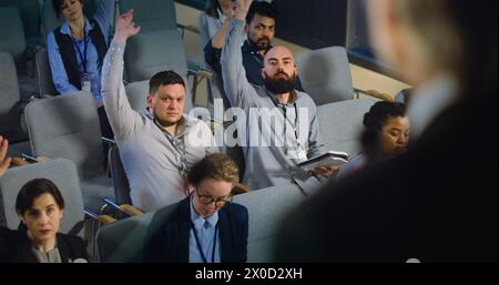 Diversi giornalisti, operatori dei media alzano la mano e fanno domande durante la conferenza stampa con un politico. L'addetto stampa o attivista rilascia un colloquio per la televisione nella sala dell'edificio governativo. Primo piano Foto Stock