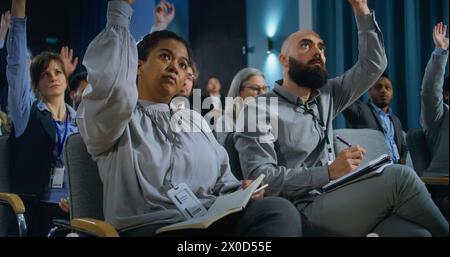 Diversi giornalisti alzano la mano per porre domande alla campagna stampa nella sala conferenze. Gli addetti alla stampa ascoltano e scrivono i discorsi dell'attivista o del politico sui taccuini durante le interviste per i media. Foto Stock