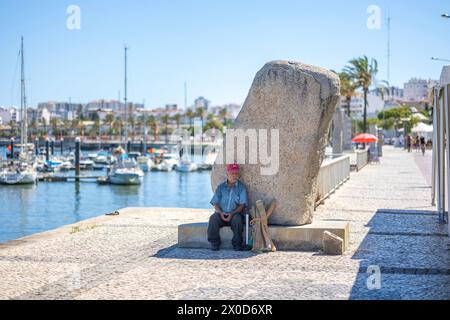 PORTIMAO, PORTOGALLO - 29 LUGLIO 2023: Veduta dei moli con diverse barche ancorate nella città di Portimao, Algarve, Portogallo. Il vecchio si rilassa accanto a Big Foto Stock