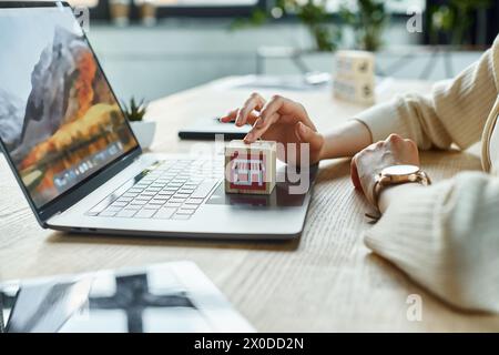 Una donna d'affari moderna ha un modello di casa di piccole dimensioni davanti a un notebook, incarnando l'innovazione nei concetti di franchising. Foto Stock