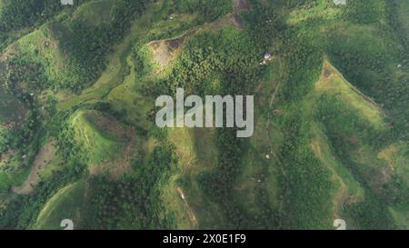 Vista aerea dall'alto verso il basso della collina verde dell'Asia: Nessun paesaggio naturale nella campagna di Legazpi, Filippine. Le montagne si innalzano a nebbia con vegetazione della foresta tropicale. La nebbia si monta sulle cime di un drone cinematografico Foto Stock